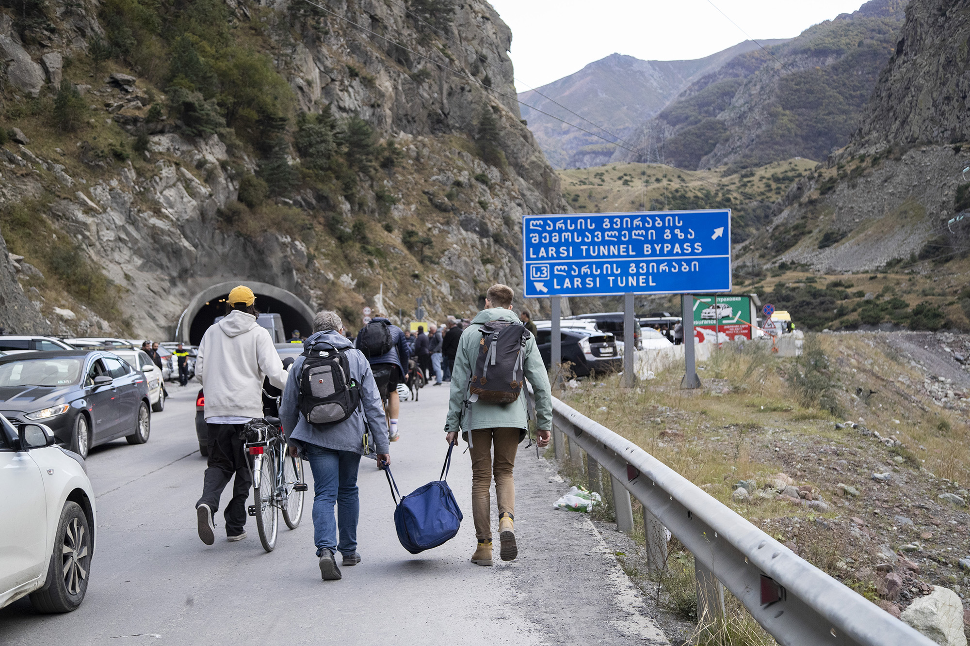 Viajeros caminando por la carretera desde el puesto de control aduanero de Verkhni Lars entre Georgia y Rusia el 28 de septiembre, en Zemo Larsi, Georgia.