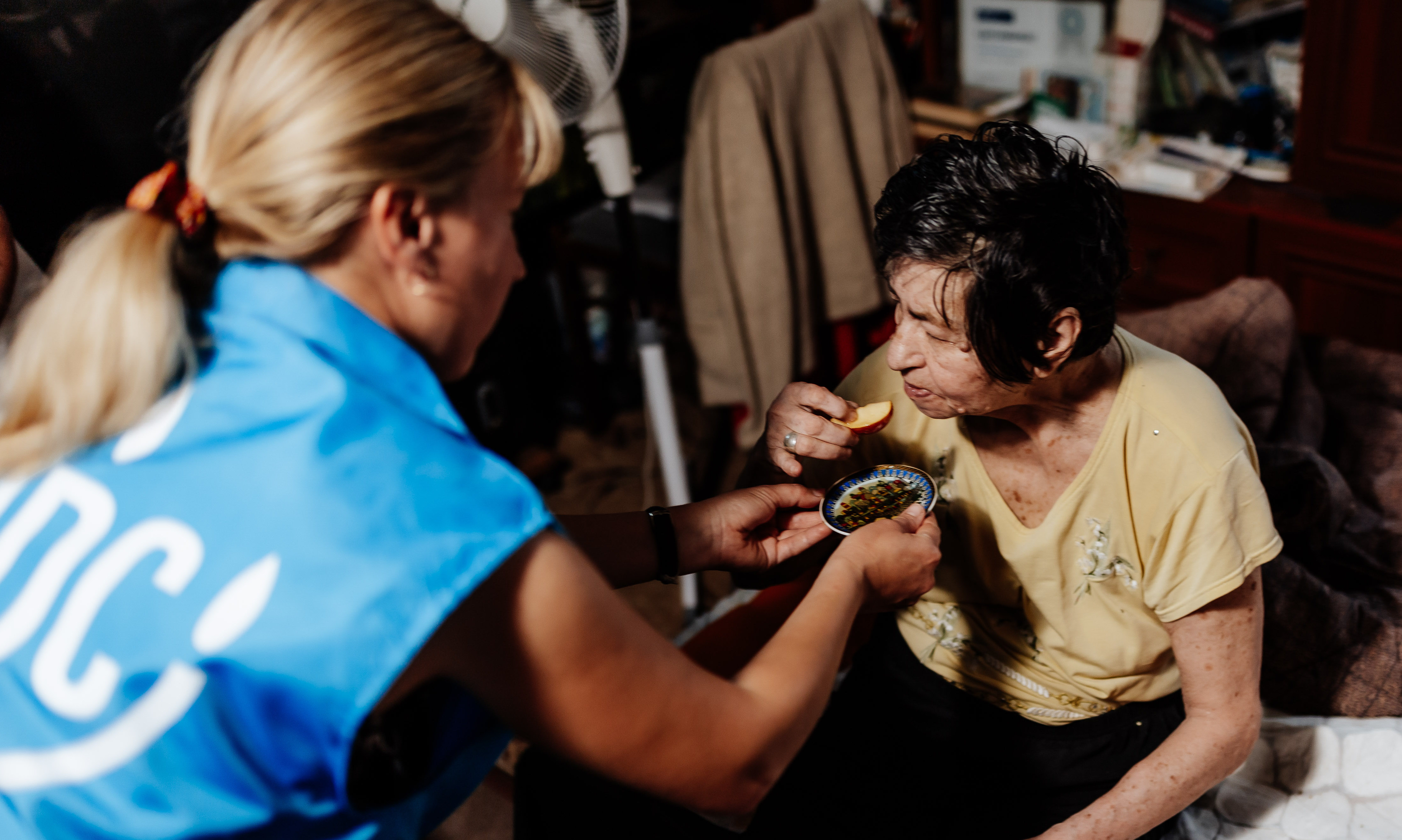 Un trabajador humanitario de JDC ofrece una muestra de manzanas y miel a una anciana judía en la ciudad sitiada de Dnipro. Las manzanas y la miel se incluyeron en los paquetes de ayuda alimentaria de Rosh Hashanah de JDC proporcionados a miles de ancianos judíos pobres en toda Ucrania.