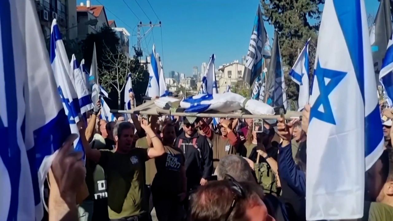 Un grupo de Hermanos y Hermanas en Armas protesta llevando una figura envuelta en la bandera israelí en una camilla, de la misma manera que llevarían a un camarada herido fuera del campo.